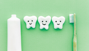 the-dental-project-oral-hygiene | The Dental Project | The Dental Project Three cartoon teeth with happy faces between a toothpaste tube and a toothbrush on a green background.