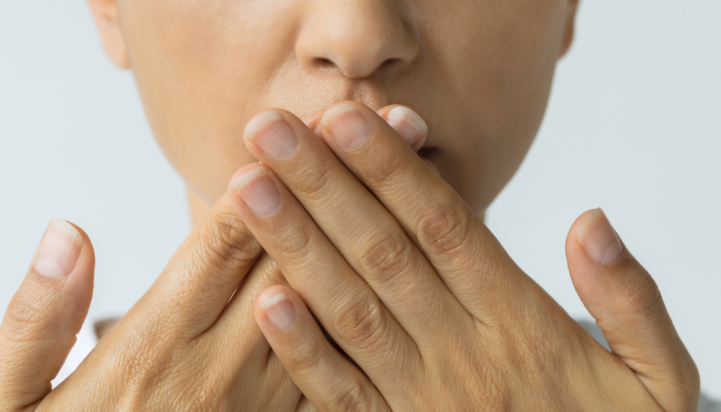 Close-up of a person covering their mouth with both hands, signaling silence or secrecy