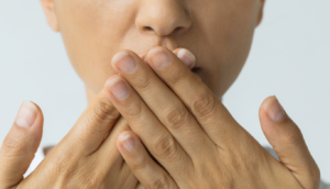 the-dental-project-bad-breath-treatment | The Dental Project | The Dental Project Close-up of a person covering their mouth with both hands, signaling silence or secrecy
